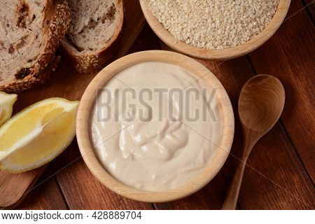 Tahini And Sesame Seeds In Wooden Bowls On Wooden Table.