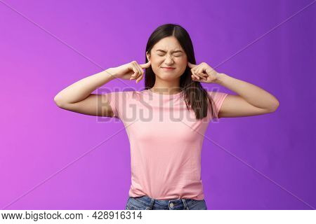 Displeased Annoyed Asian Brunette Woman Fed Up Hearing Loud Parents Yell, Close Eyes Grimacing, Plug