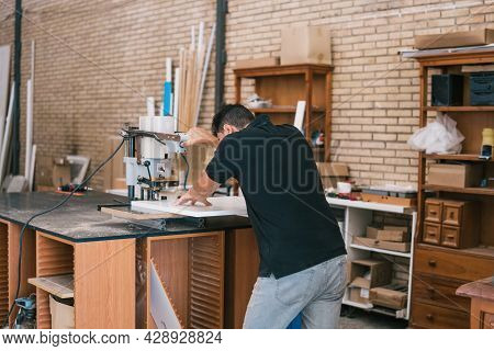 Man Cutting A Piece Of Wood With An Electric Cutter On A Workshop