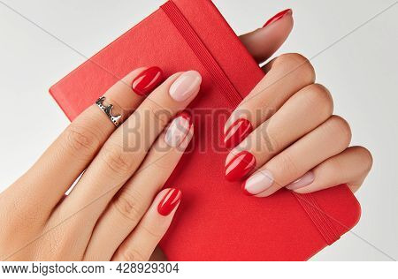 Womans Hand Holding Notepad Over White Background. Manicure Design Trends