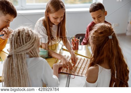Smiling Schoolchildren Using Geoboard In Classroom Together