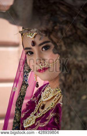 Portrait Asian Woman In A Margenta Indian Tradition Sari, She Is Hide Her Face By Tree And Looking A