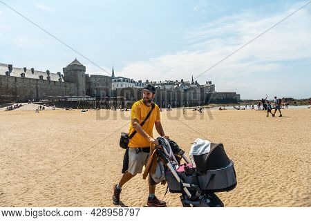 A Young Father Enjoying The Summer On The Grande Plage Du Sillon De Saint-malo In French Brittany, F