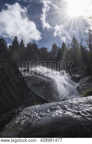 Backlighting Of A Waterfall Seen From Below, With The Sun's Rays Filtering Through The Clouds And Ro