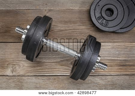 Übung Gewichte - Eisen-Hantel mit zusätzlichen Platten auf einem Holzdeck
