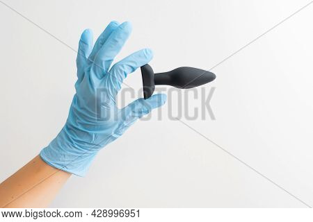 Black Butt Plug In Gloved Hand Isolated On White