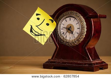 Drawn smiley face on a post-it note sticked on an alarm clock