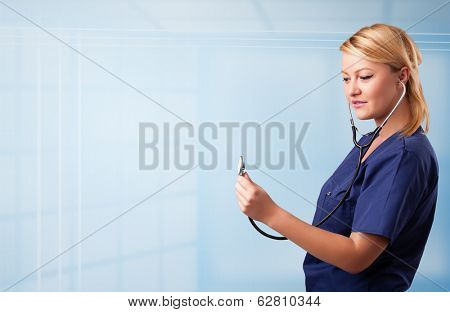 Pretty young nurse in hospital listening to empty copy space with sthetoscope