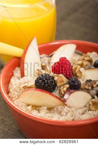 Bowl of delicious steel cut oats with fresh fruit, honey and orange juice