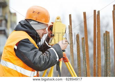 One surveyor worker working with theodolite transit equipment at road construction site outdoors
