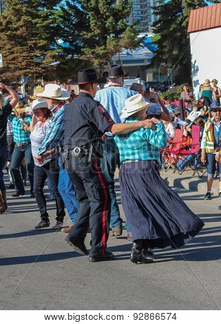 Policeman And Lady Dancing On The Street During Calgary Stampede Parade