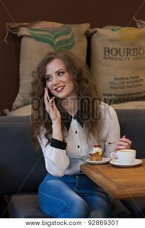 Smiling Girl Talking On The Phone Sitting In A Cafe And Drinking Coffee