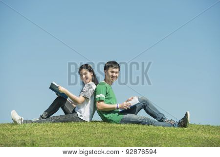 Young Asian Couple Sitting Side By Side And Reading Their Books