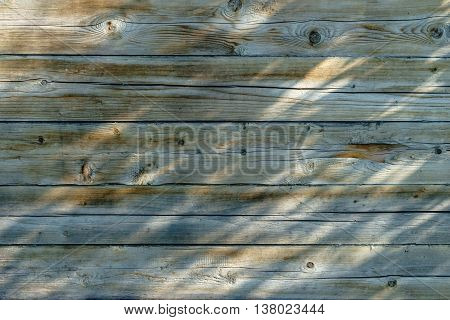 The wooden wall of the house. Cracked boards pattern of light and shadow