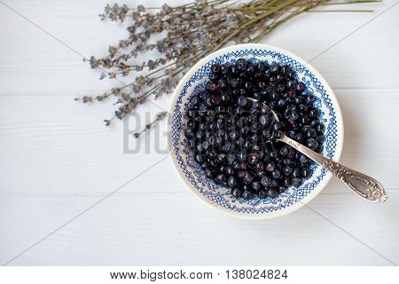 A flat lay of a blueberry bowl and flowers of lavender on a white background