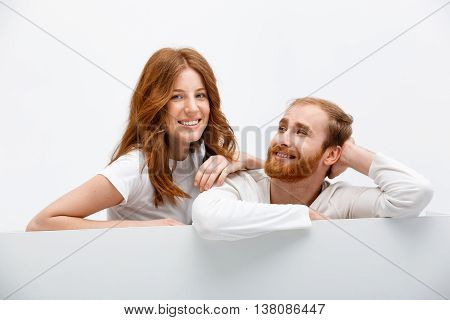 Funny redhead boy and girl posing at white table smiling