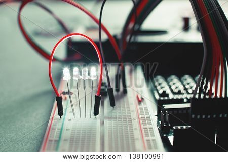 Closeup on electronic board in hardware repair shop. Breadboard with special cables and led. Electronics diy development