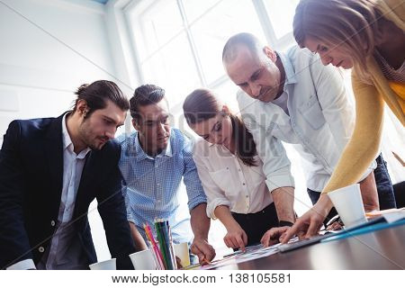 Tilt image of photo editors looking at photos on table in creative office