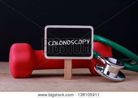 Medical concept - Stethoscope and dumbbell on wood with Colonoscopy words