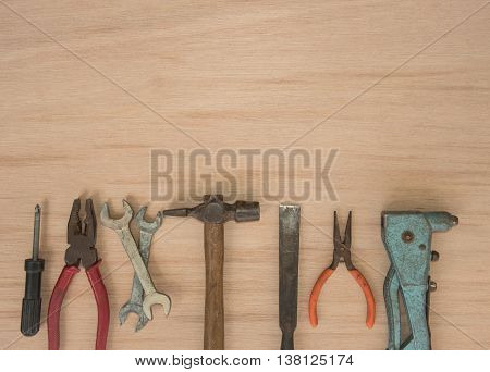work tools hammer wrench screwdriver pincers pliers hand screw pliers old spanner on a wooden table top view with empty space