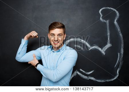 Picture of  funny suited business  man with  fake muscle arms over blackboard.