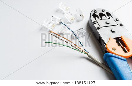 Crimper connectors and ethernet cable on white background