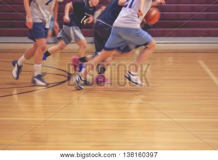 a girls basketball team running up or down the court (no point of focus) toned with a retro vintage instagram filter effect app or action 