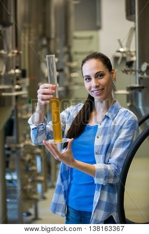 Portrait of beautiful female brewer hydrometer cylinder at brewery factory