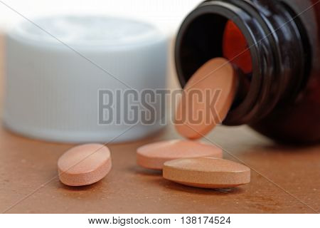 Statins or generic pills pouring from a bottle. Close up with shallow depth of field