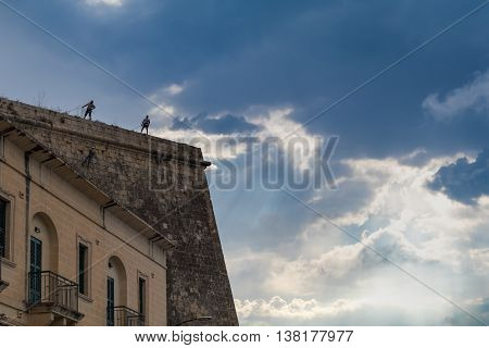 workers absail to repair the crumbling fortifications surrounding Valletta backed by a dramatic sky June 2016.