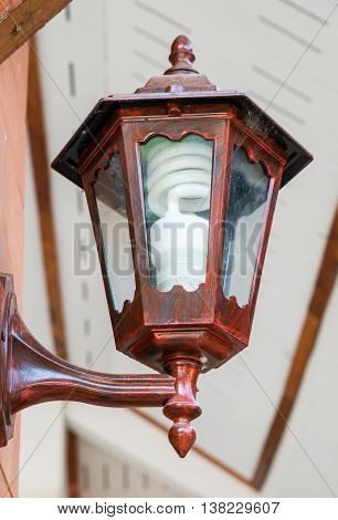 Wooden lantern with modern electricity blub is hanging on the house wall.
