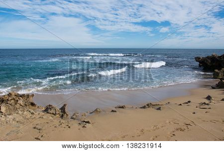 Stunning turquoise Indian Ocean seascape from a remote Penguin Island beach under a blue sky with clouds in Rockingham, Western Australia.