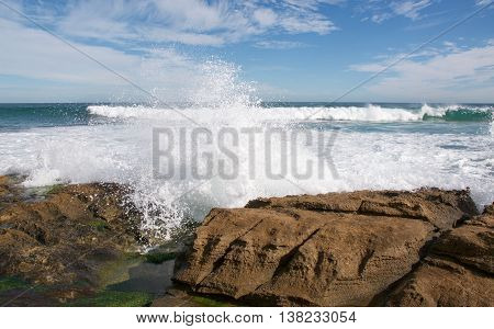 Indian Ocean waves crashing the rugged limestone rock formations on the beach at Penguin Island in Rockingham, Western Australia.