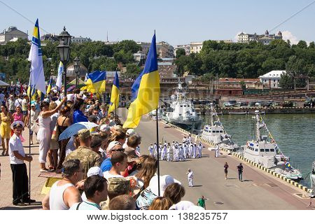 Odesa, Ukraine - July 03, 2016: people with flags on the docks of Odessa seaport during celebration Ukrainian NAVY day and the warships at the background
