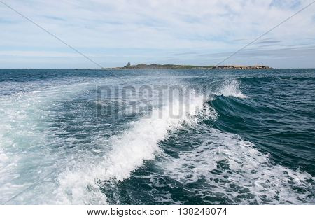 Foamy waves from a boat wake in the Indian Ocean waters under an overcast sky in Rockingham, Western Australia.