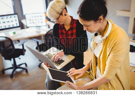 Two female graphic designer using digital tablet and laptop in office
