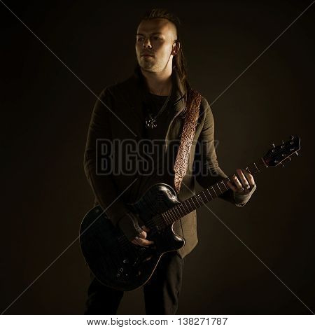 Guitarist playing rock music. On dark background. Beautiful guitar.