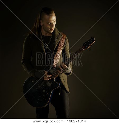 Guitarist playing rock music. On dark background. Beautiful guitar.
