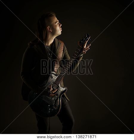 Guitarist playing rock music. On dark background. Beautiful guitar.