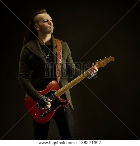 Guitarist playing rock music. On dark background. Beautiful guitar.
