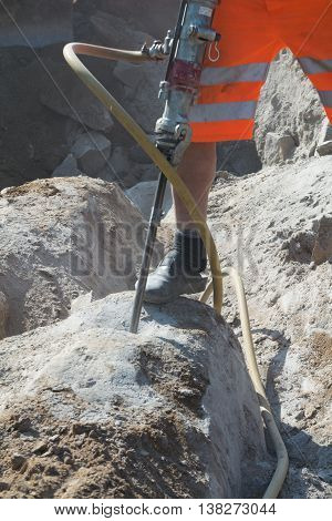 Construction works with demolition hammer on stone