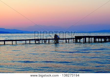 Couple in love, watching the sunset on the Pier in Corfu.