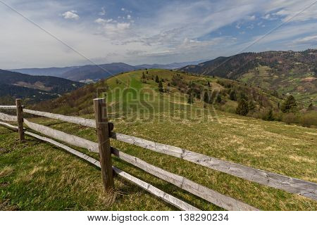 Pasture in mountains and a wooden fence in the foreground. Carpathians