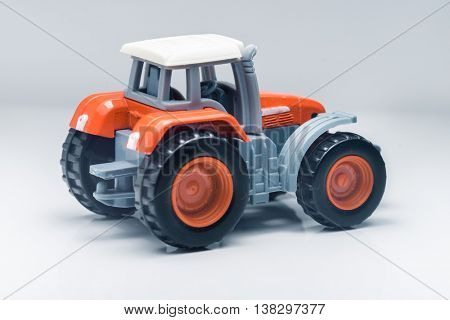 Small red toy tractor on light background, shallow depth of field