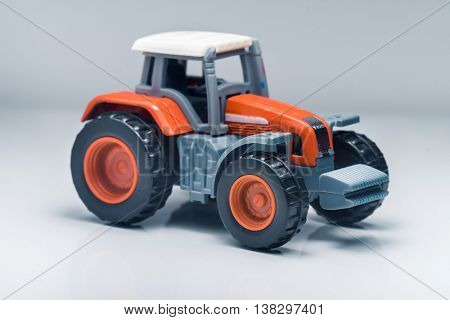 Small red toy tractor on light background, shallow depth of field