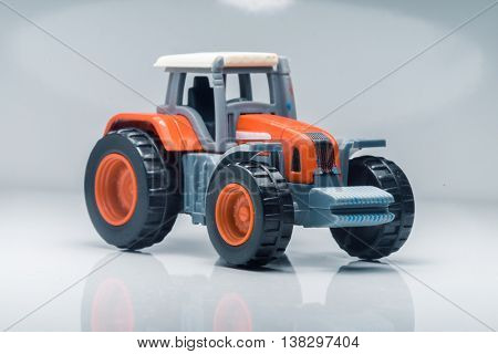 Small red toy tractor on light background, shallow depth of field