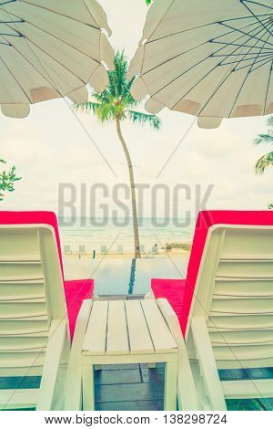 Beautiful beach chairs with umbrella around outdoor swimming pool neary sand and sea
