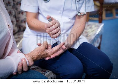 Mid section of doctor testing a patients glucose level using a digital glucometer
