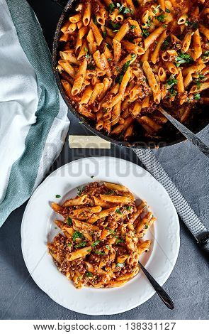 Top view of american chop suey - pasta dish with beef, tomato sauce, mozarella cheese, spices and parsley. Italian-American cuisine
