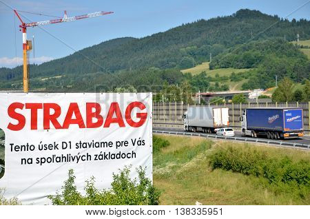 Dolny Hricov, Slovakia - June 29, 2016: Tower crane working on construction site of slovak D1 highway billboard of Strabag building company in foreground (translation: 